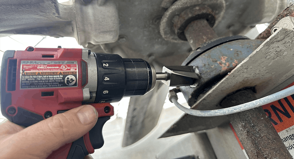 A photo of a hand using an MH117 Series spot face tool attached to a right-angle drill to prepare a machine surface.