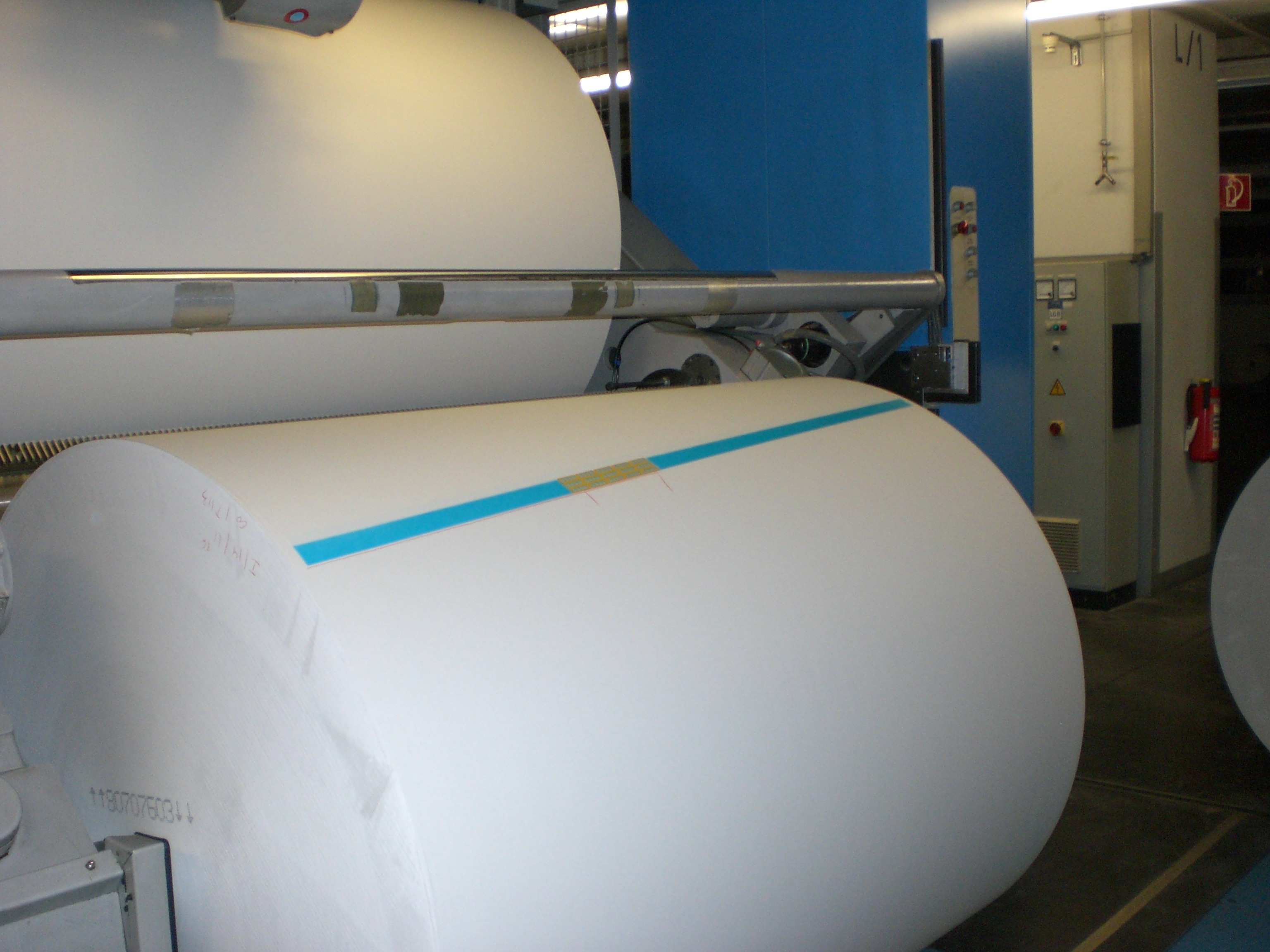 A large roll of paper on an industrial reel inside a factory